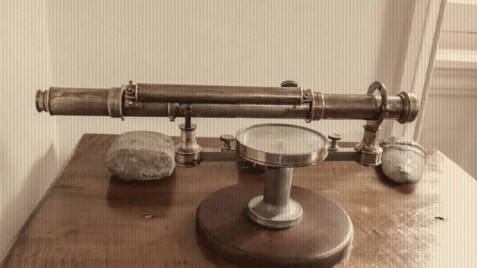 Antique brass surveying instrument on a polished wooden table