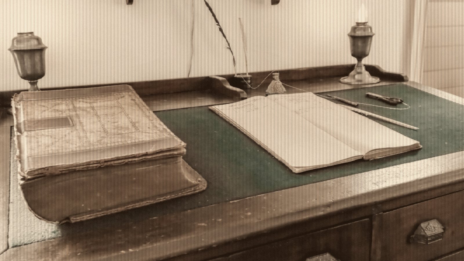 Antique desk with open book, quill, and two vintage lamps
