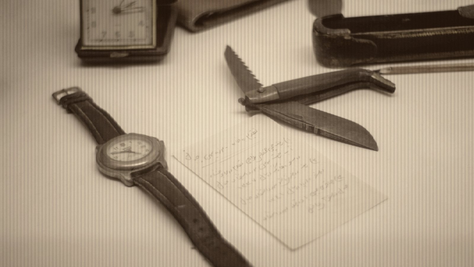 Wristwatch, pocket knife, and notepad arranged on surface